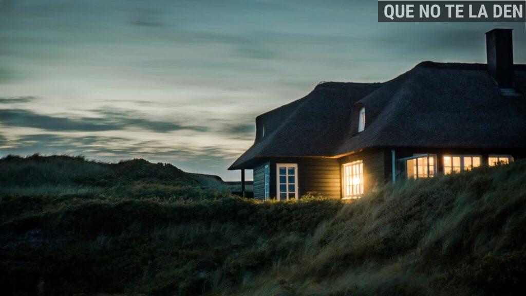 A scenic view of a cozy bungalow illuminated at dusk, nestled in lush greenery.